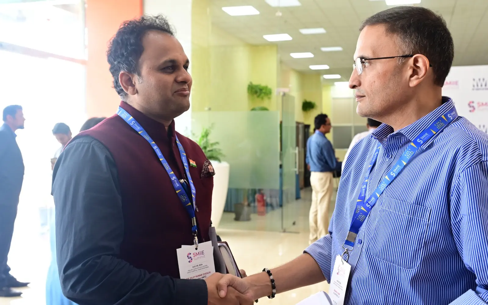 Two SMilE Summit participants shake hands during a networking conversation